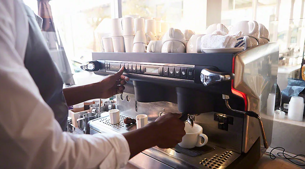 Close Up Of Barista Making Coffee In Deli Using Machine