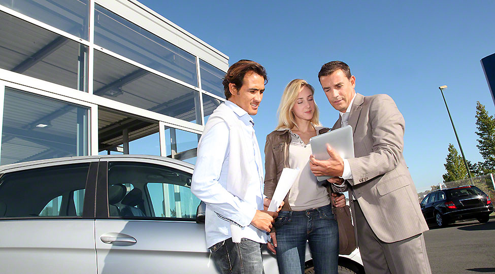 Car seller with couple looking at electronic tablet