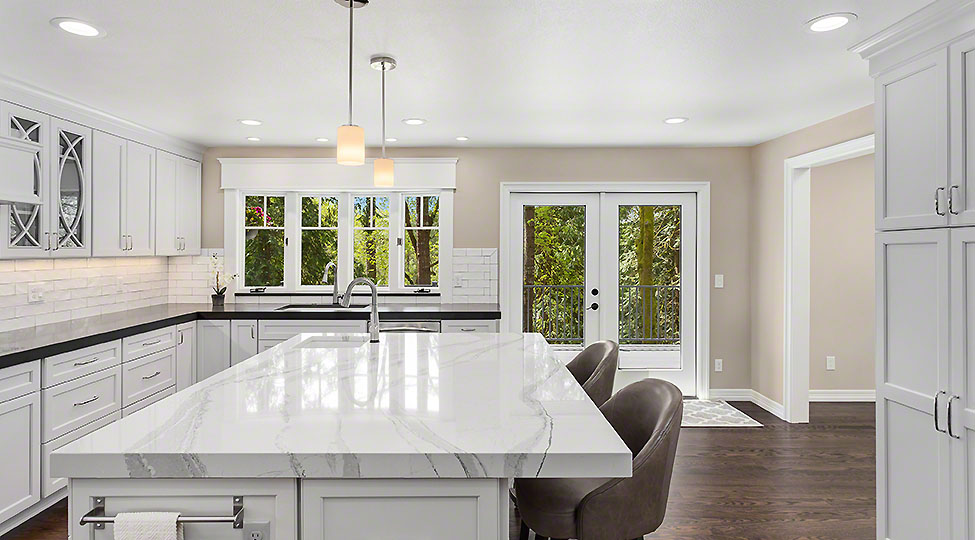 beautiful kitchen in new luxury home with island, pendant lights, oven, range, and hardwood floors.