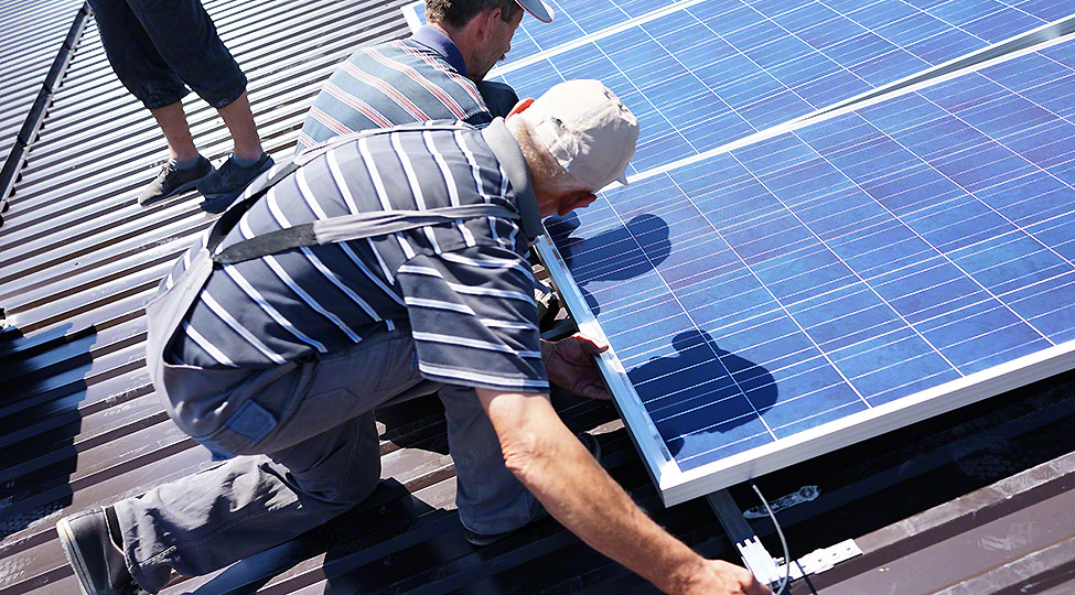 Man installing alternative energy photovoltaic solar panels on r