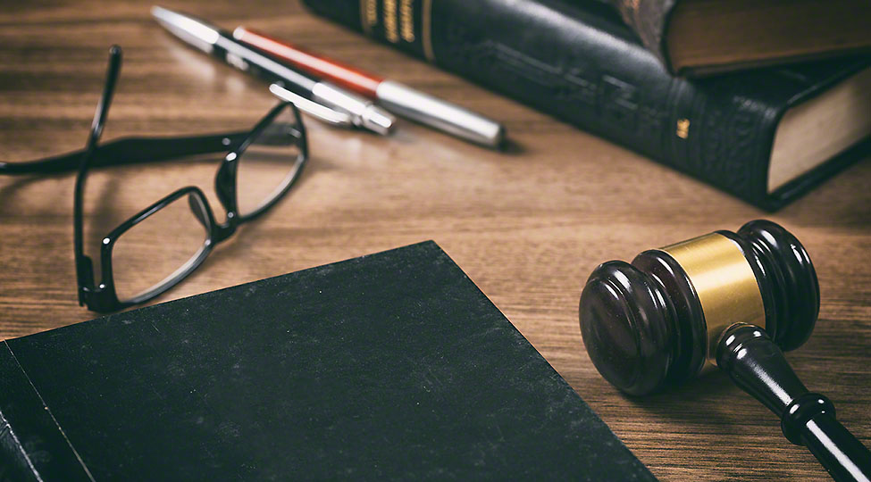 Law or auction gavel and a book, wooden office desk background.
