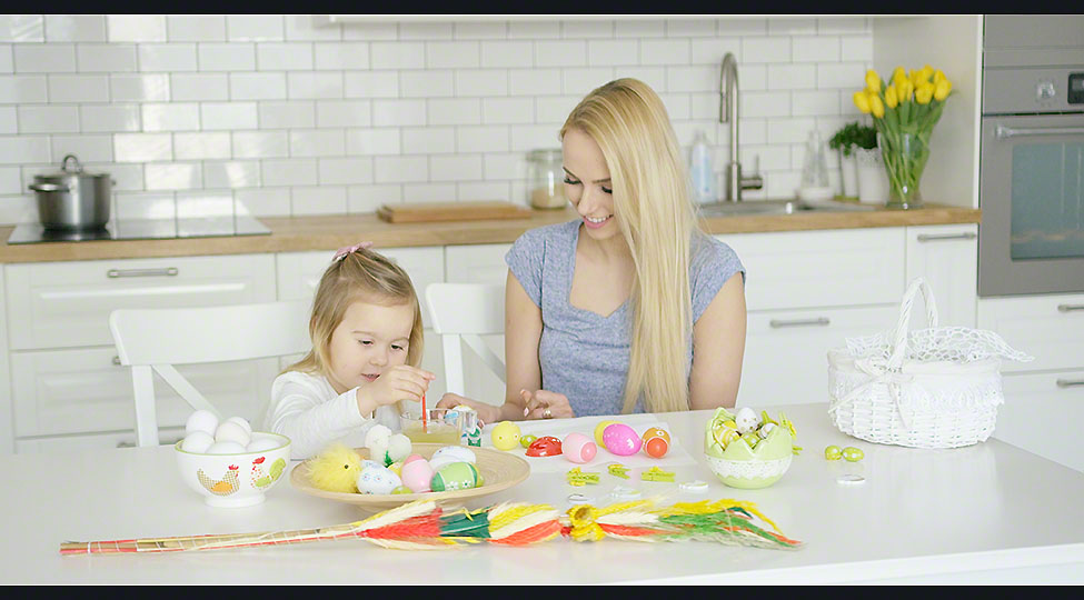 Loving mother and daughter coloring eggs