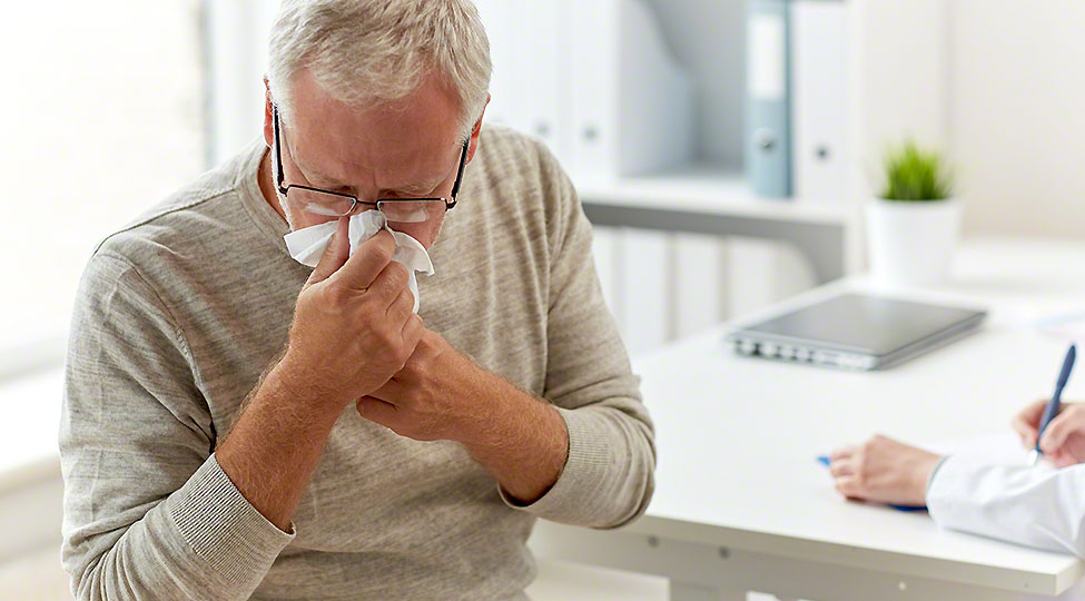 senior man blowing nose with napkin at hospital