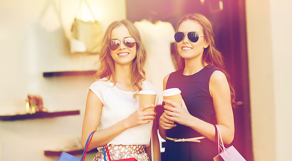 young women with shopping bags and coffee at shop